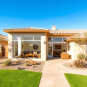 A modern Phoenix home featuring a stylish sunroom with large windows, surrounded by desert landscaping, creating a warm and inviting indoor-outdoor...