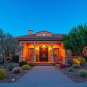 A stunning Arizona home with vibrant landscaping, a welcoming front porch, and warm desert colors, set against a clear blue sky and highlighted by ...